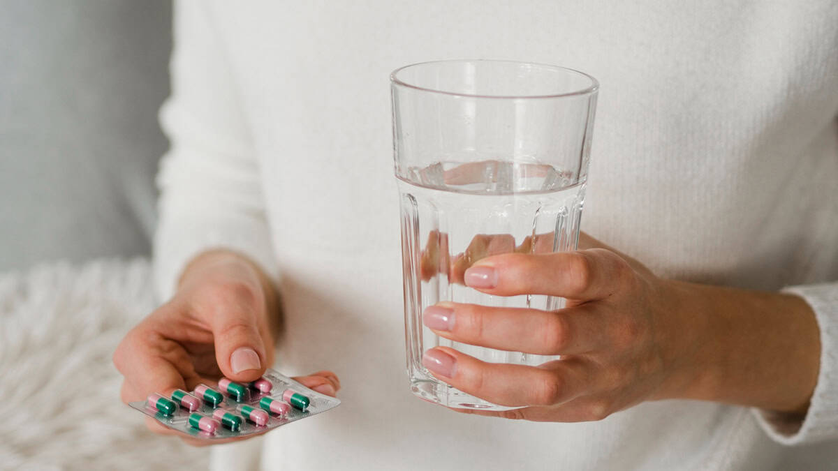 Person with a glass of water and medication