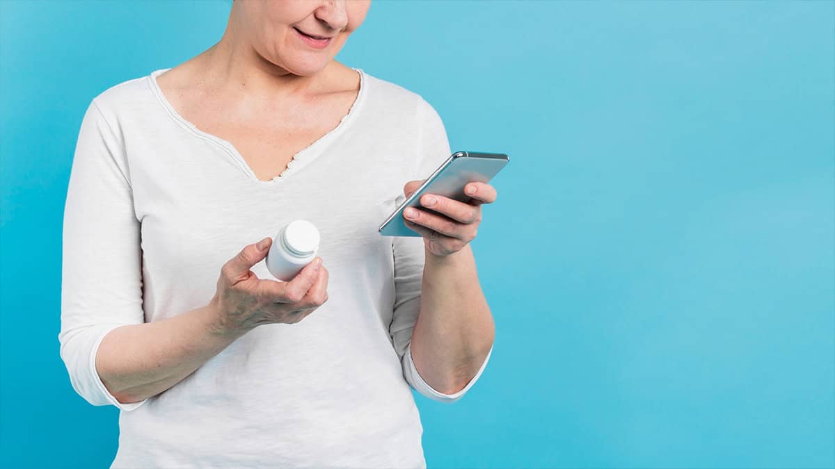 Person holding a pills bottle and her phone