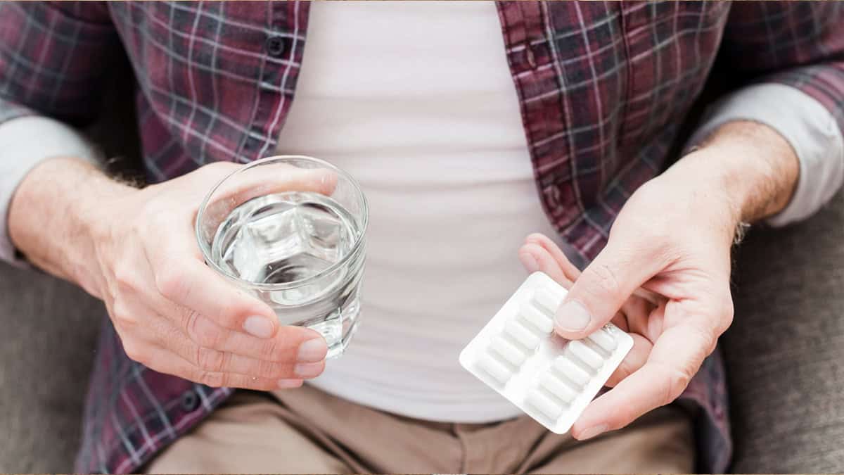 Person holding a tablet pack and a glass of water