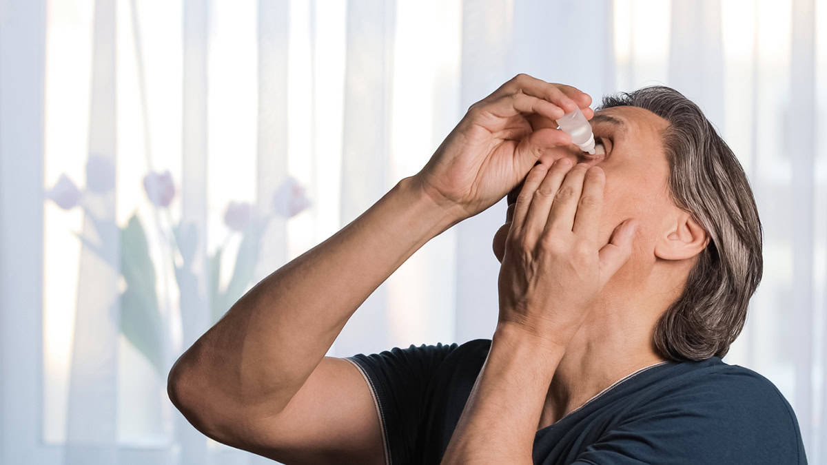 Person putting eye drops in his eyes