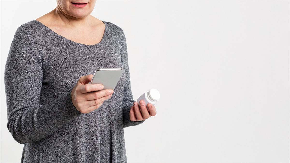 Women holding a phone and a medication bottle